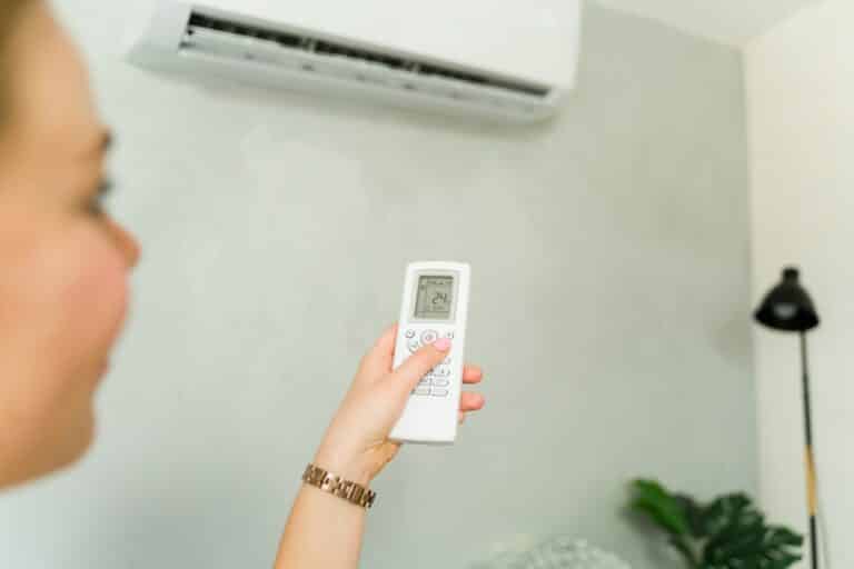 Woman,Setting,Temperature,Of,Air,Conditioner,At,24,Degrees,Celsius